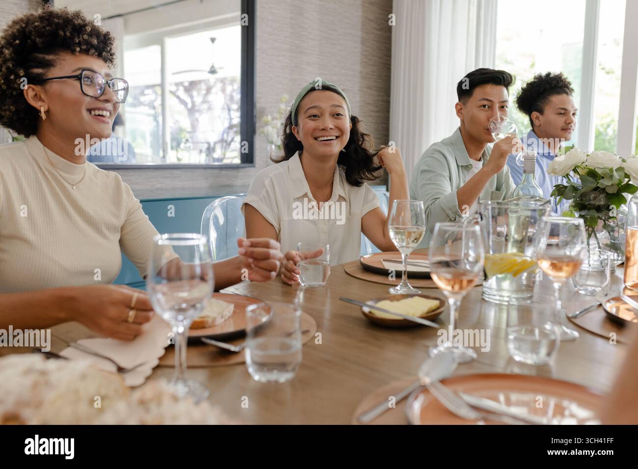 Al piccolo ricevimento di nozze informale, amici che conversano e si ridono a tavola, a casa Foto Stock