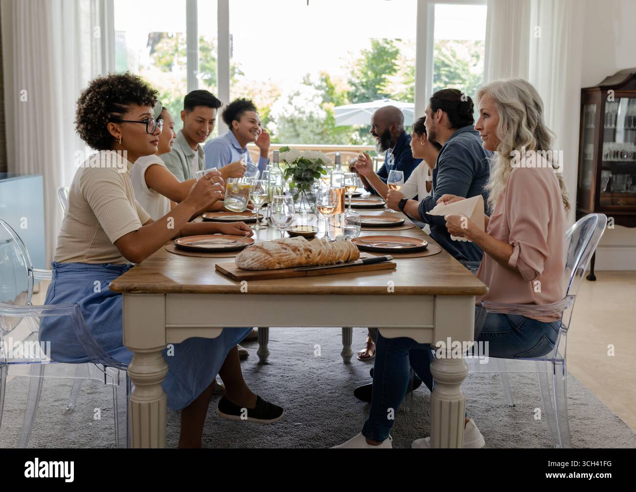 Famiglia e amici che mangiano insieme a casa, condividono risate e storie, a casa Foto Stock