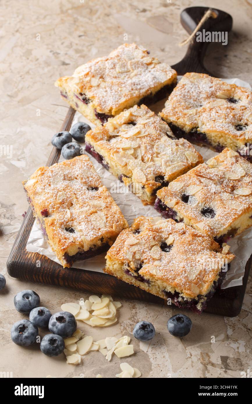 Torta morbida e umida con mandorle di mirtillo, primo piano sul bordo di legno del tavolo. Verticale Foto Stock