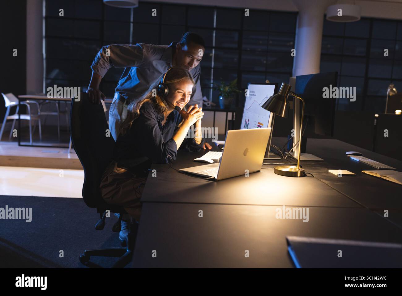 Collaborando al progetto, i colleghi si sono concentrati sullo schermo del computer in ufficio lavorando fino a tardi Foto Stock
