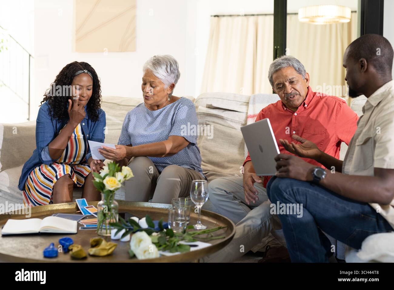 Condividere foto, donna afroamericana con anziani e uomo che usa un tablet durante la riunione Foto Stock