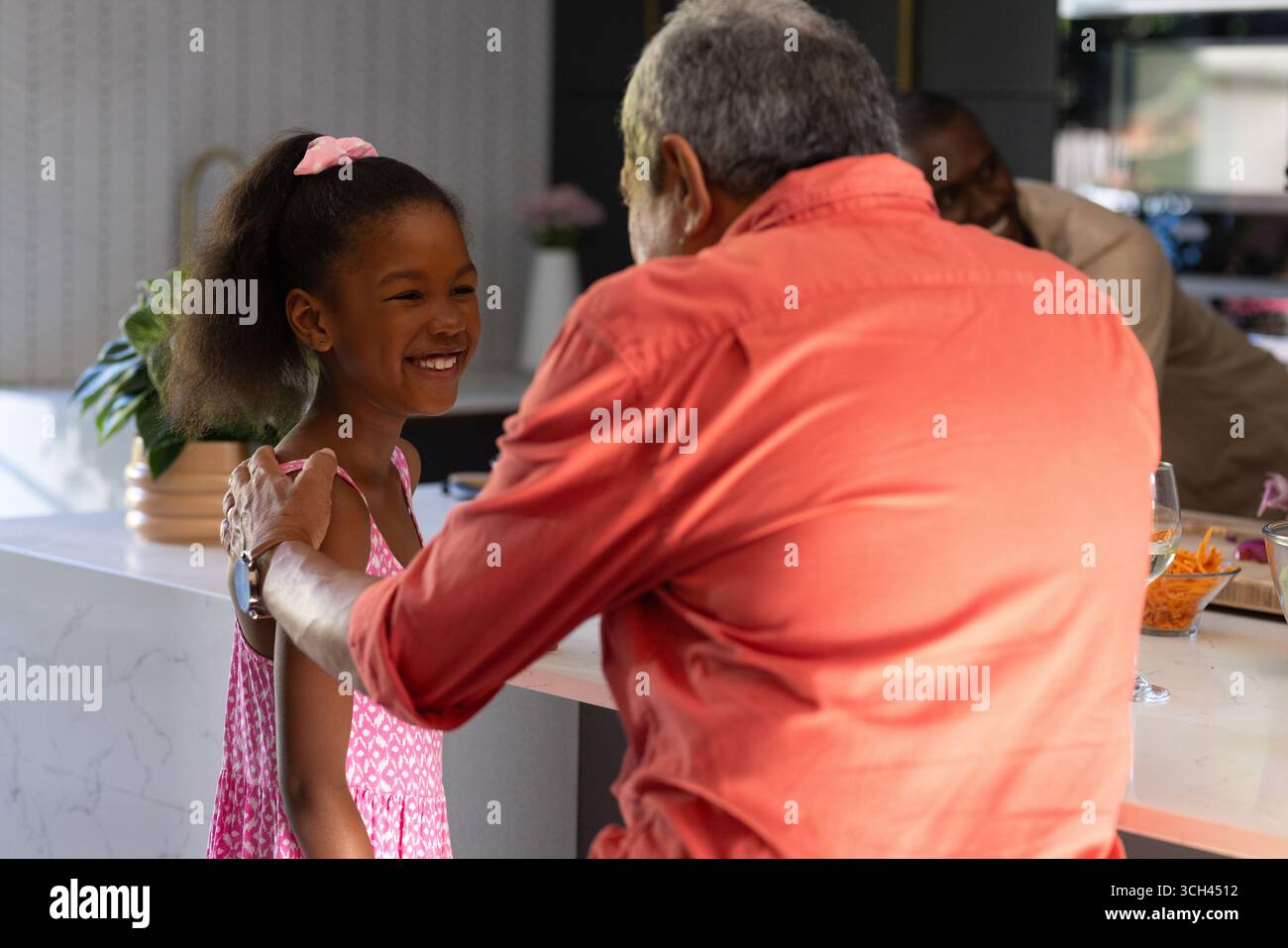 Nonno e nipote condividono momenti di gioia insieme in una cucina moderna Foto Stock