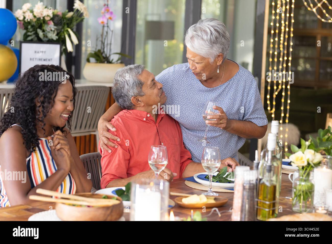Nonna che abbraccia il nonno a cena di famiglia, festeggia la pensione con gioia Foto Stock