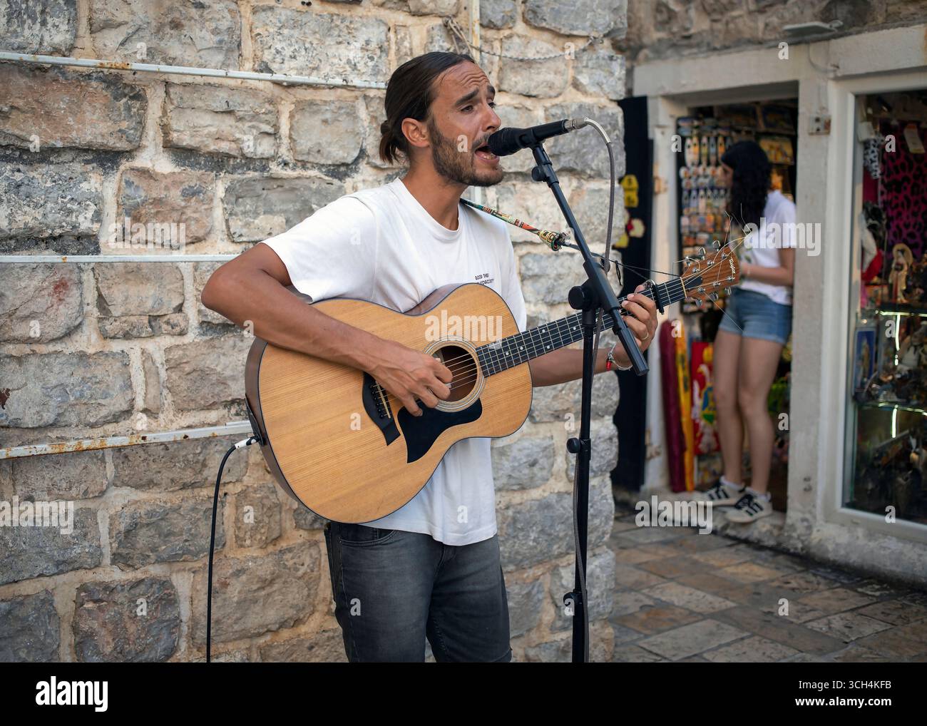 Musicista di strada che si esibisce con una chitarra nella città vecchia di Budva, Montenegro, 15 luglio 2025. Foto Stock