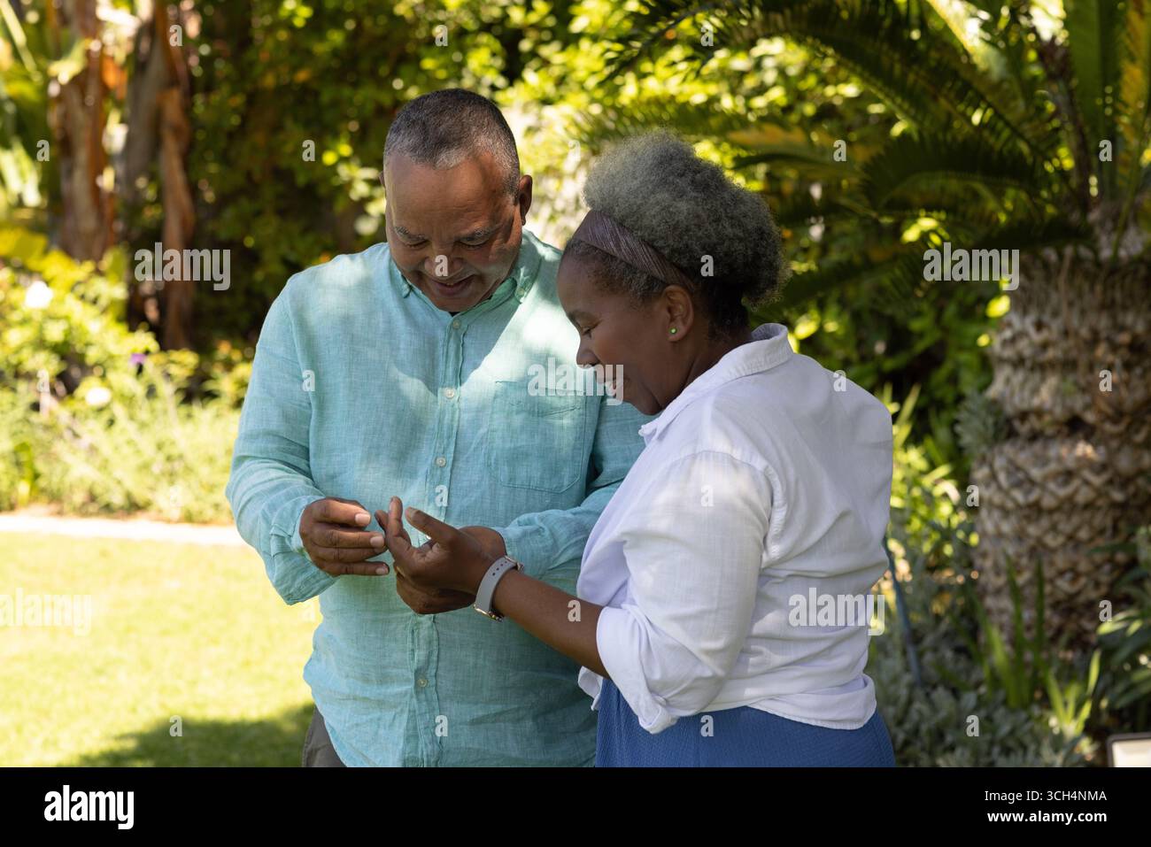 Coppia senior in giardino che condivide momenti di gioia guardando lo smartphone Foto Stock