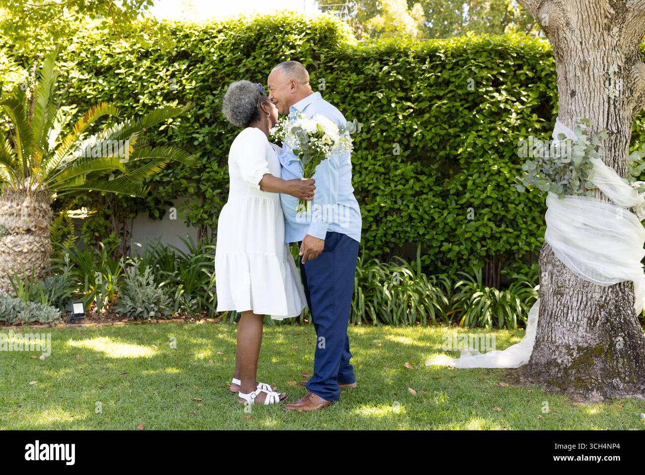 Coppia senior che abbraccia e bacia in giardino, celebrando l'amore e la solidarietà Foto Stock