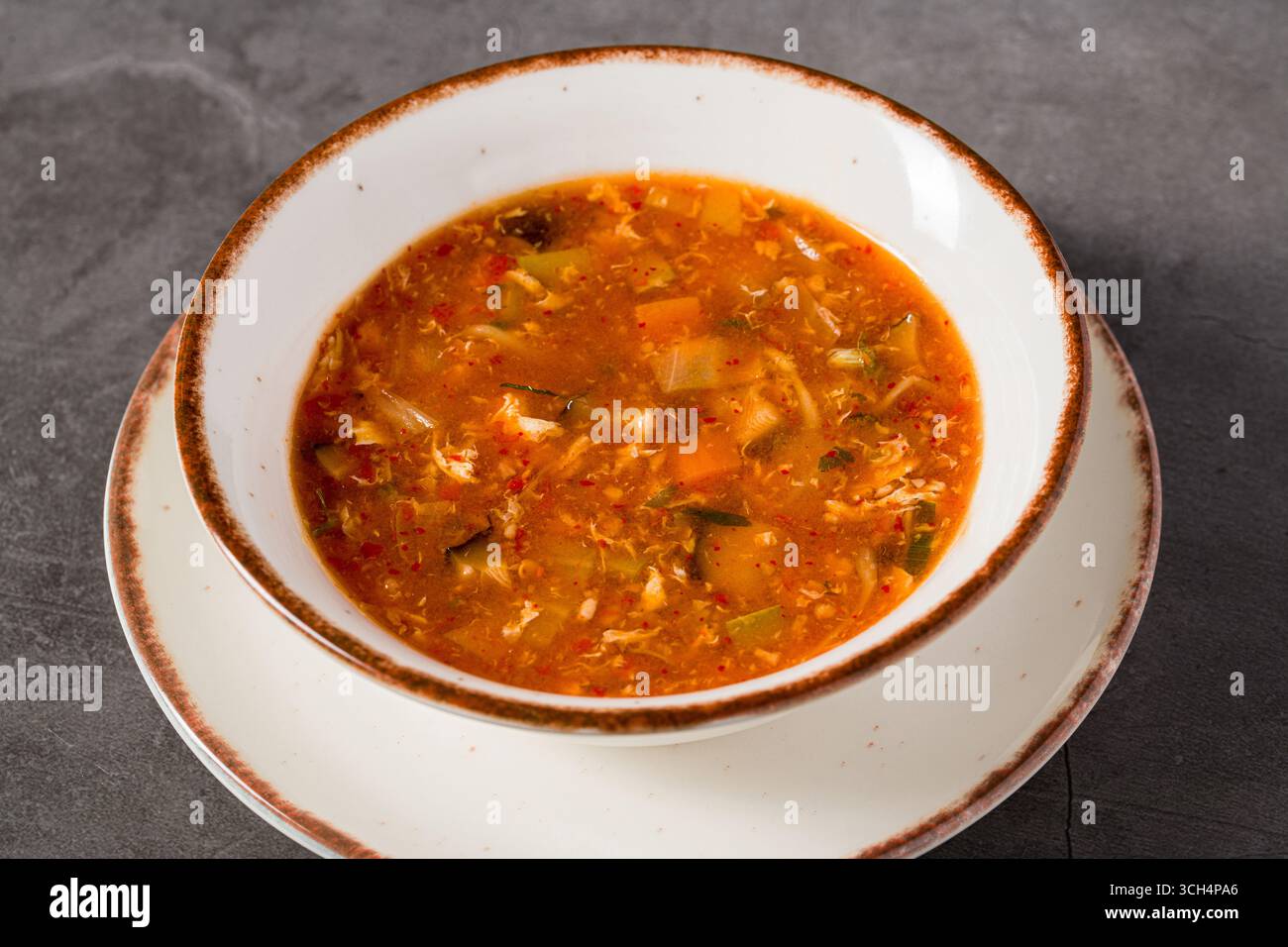 Zuppa asiatica calda e acida con verdure in un recipiente bianco Foto Stock
