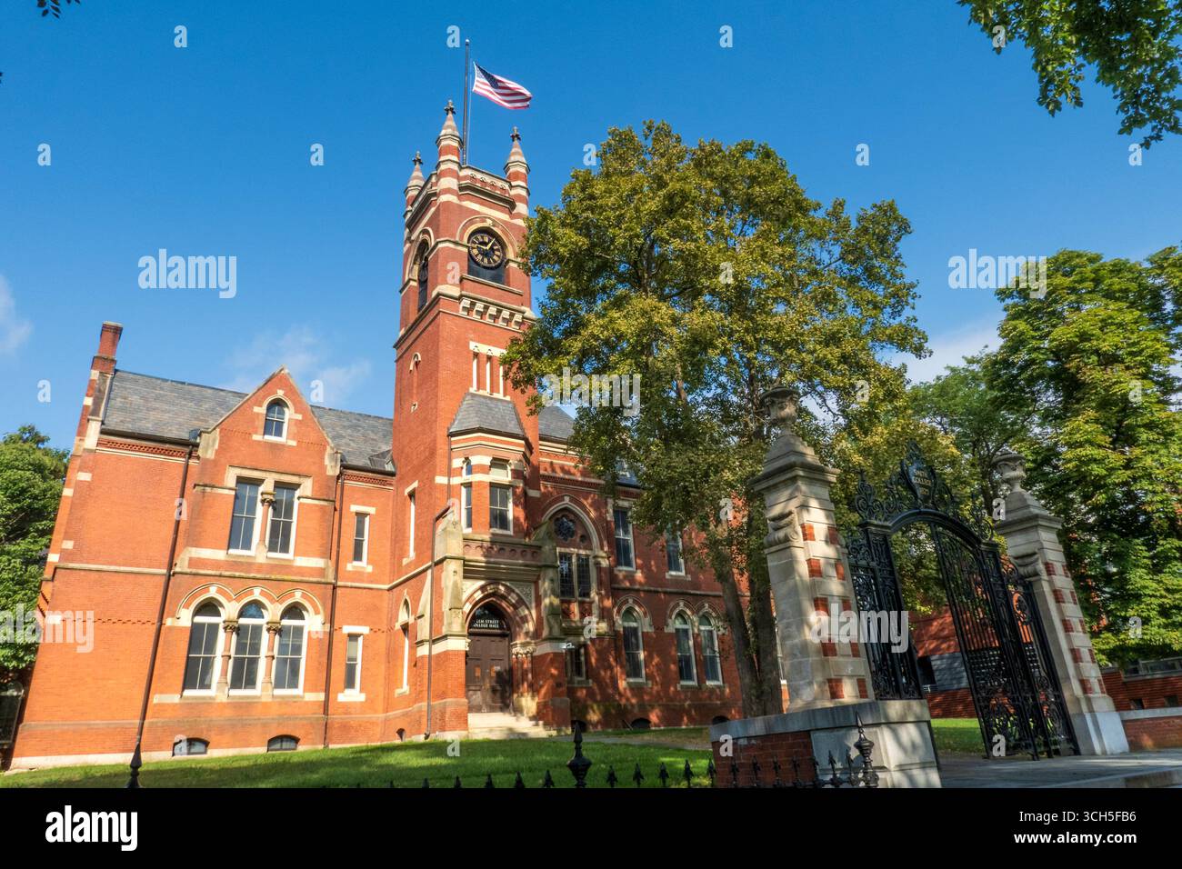 Northampton, ma - USA - 24 agosto 2025 Una grande sala in mattoni dello Smith College, con una torre dell'orologio di spicco e bandiera americana, posta contro una chiara b Foto Stock