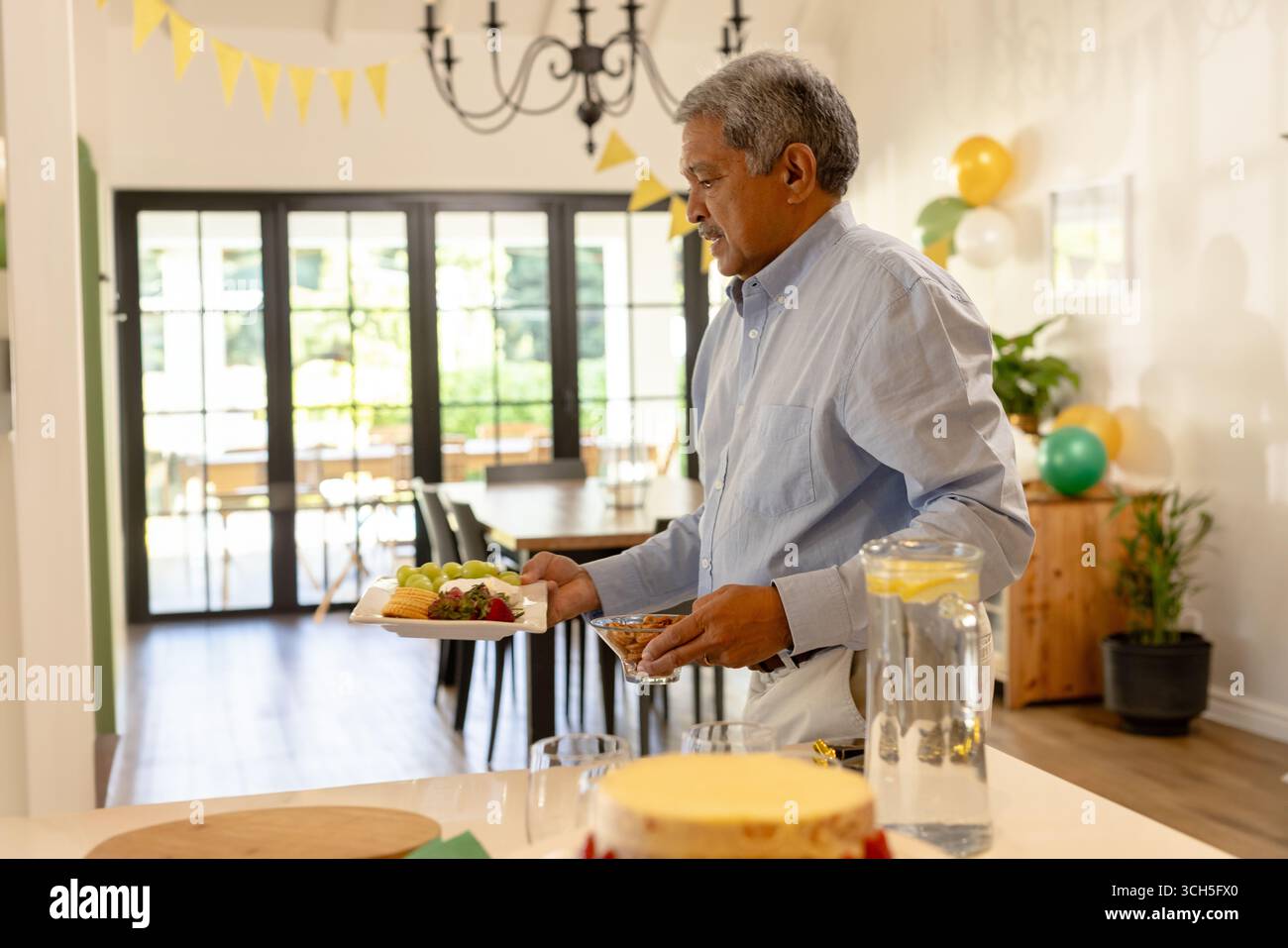 Uomo di mezza età che serve se stesso al buffet della festa al coperto, con uva e formaggio, spazio per fotocopie Foto Stock