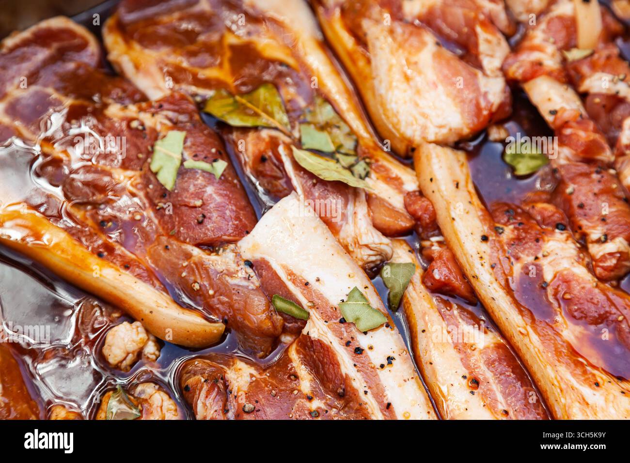 Pancetta in salamoia con spezie. Carne di maiale a fette imbevuta in salamoia con spezie. Foto Stock