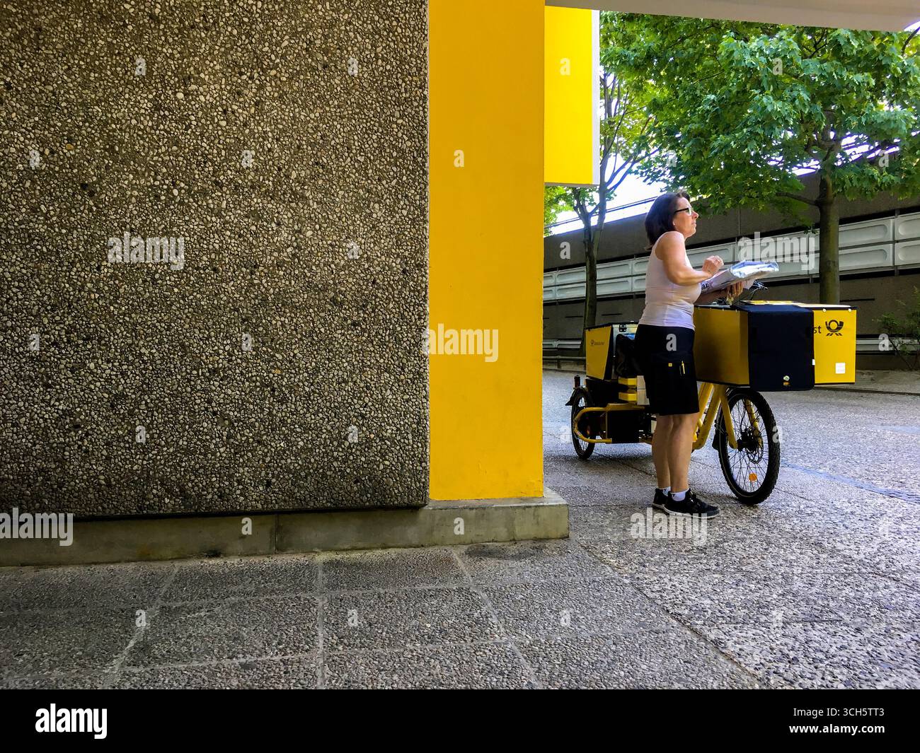 Una dipendente di Deutsche Post / Bundespost (posta tedesca) che consegna posta e buste in un alto condominio a Gropiusstadt. Grazie alla posta elettronica e a Internet, ha sempre meno posta da distribuire. Questa quantità di posta in diminuzione richiede lavori. Berlino, Germania. Foto Stock