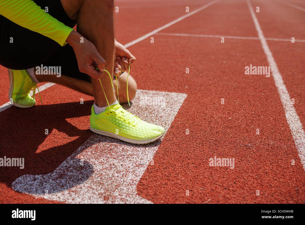 Uomo che lega scarpe da running, sport e giochi olimpici. Foto Stock