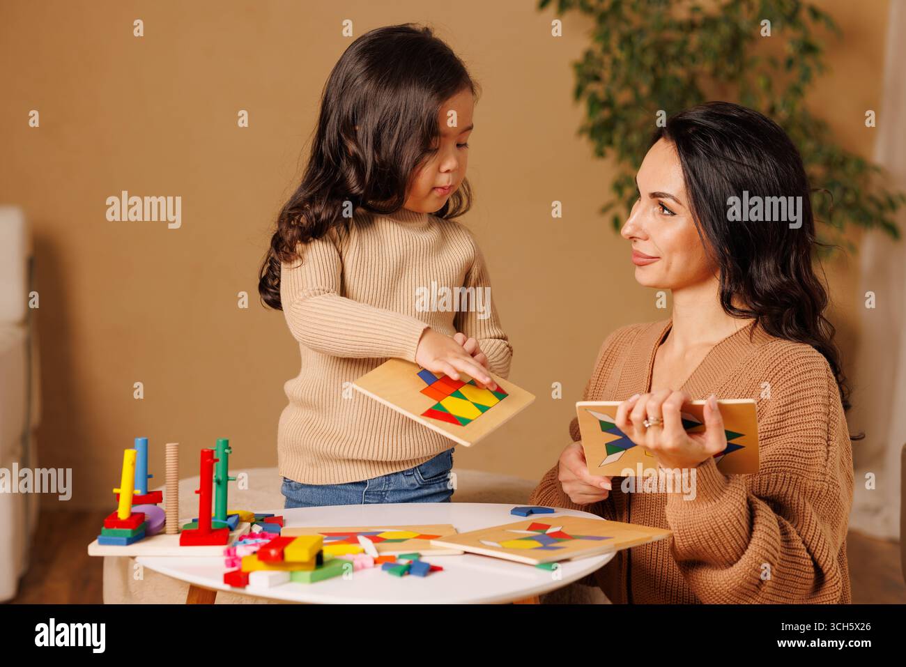 Madre e figlia giocano insieme a casa con coloratissimi tabelloni in legno incentrati sull'apprendimento della prima infanzia Foto Stock