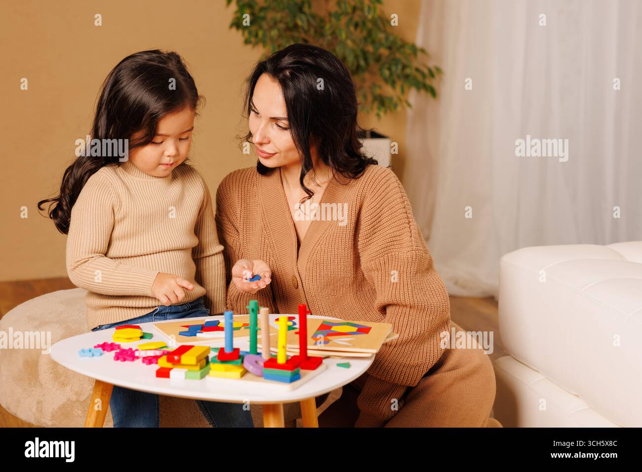 Mamma e figlia giocano con blocchi di apprendimento colorati mentre sono seduti a casa impegnati nello sviluppo della prima infanzia Foto Stock
