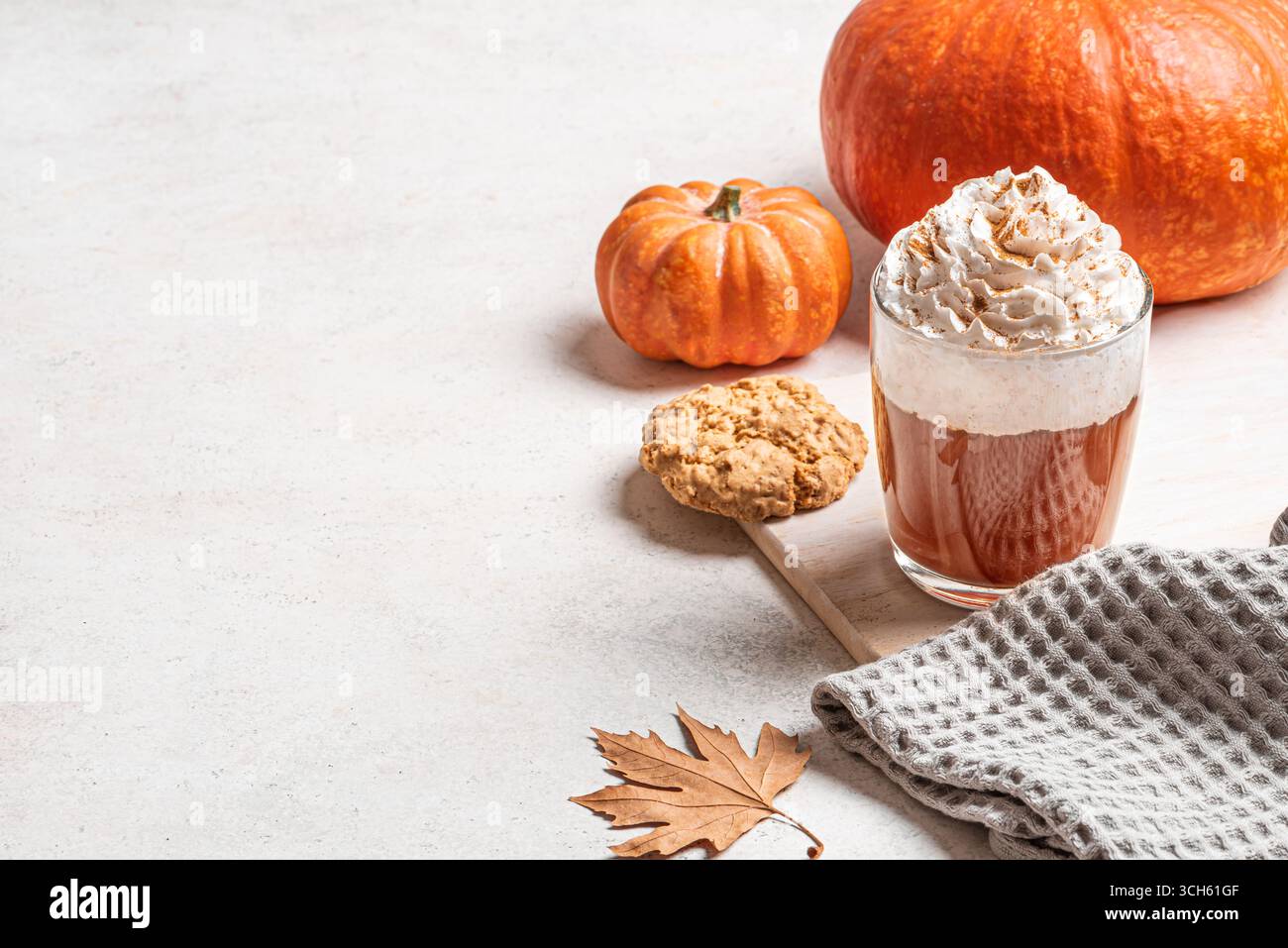 Tazza di caffè Pumpkin Spice latte con zucche, foglie di mela e biscotti su sfondo bianco. Concetto autunnale stagionale con caffè e foglie d'acero, c Foto Stock