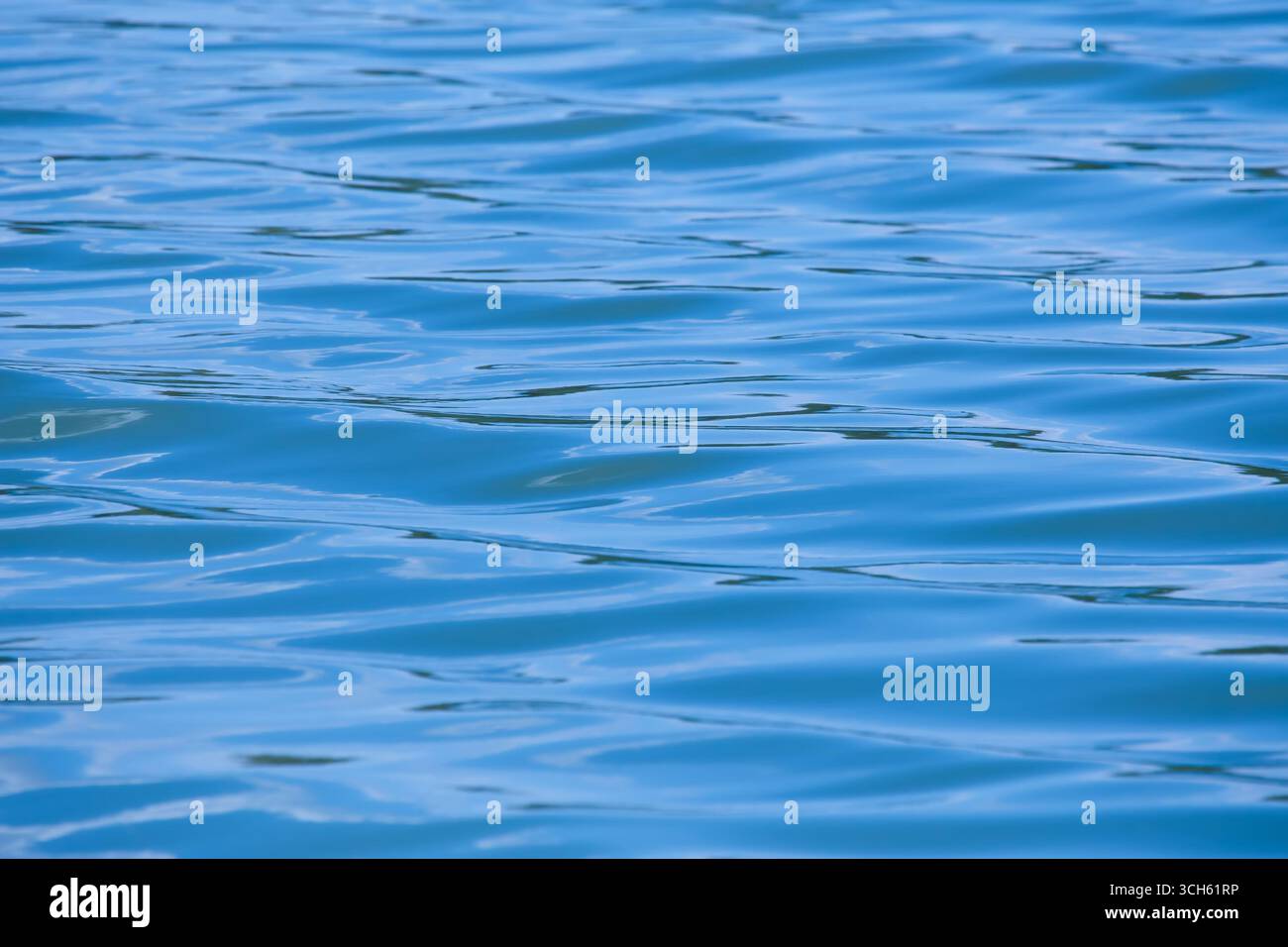 L'immagine mostra un corpo d'acqua blu calmo con piccole onde lisce. Foto Stock
