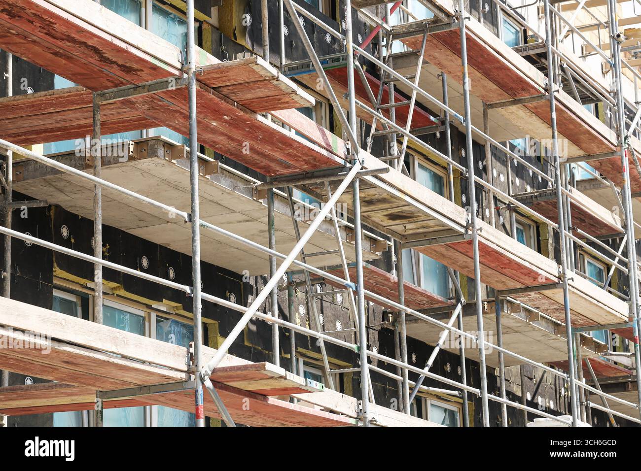 Ponteggio di costruzione su un'alta facciata dell'edificio. Struttura metallica per la sicurezza dei lavoratori. Struttura di sviluppo urbano con piattaforme. Foto Stock