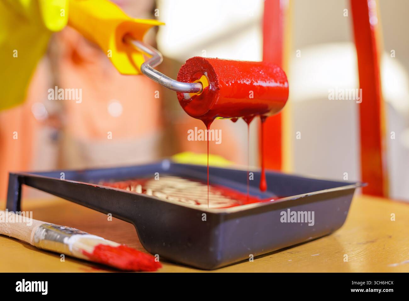 Chiudi il rullo rosso sopra il vassoio con gocciolamenti in una scena di ristrutturazione di mobili fai da te con spazio per le copie Foto Stock