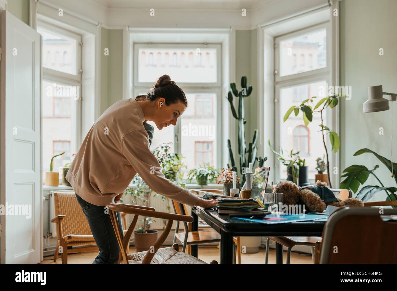 Rimani a casa tua madre indossando le cuffie intrauricolari wireless utilizzando il computer portatile mentre sei in viaggio con un figlio Foto Stock