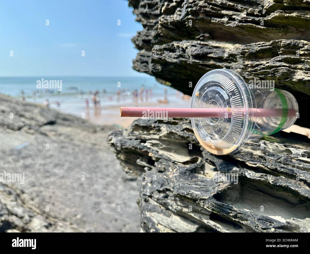 Una tazza di plastica incastrata in una roccia a Mwnt Bay, nel Galles del Sud - Immagine stock catturata con smartphone