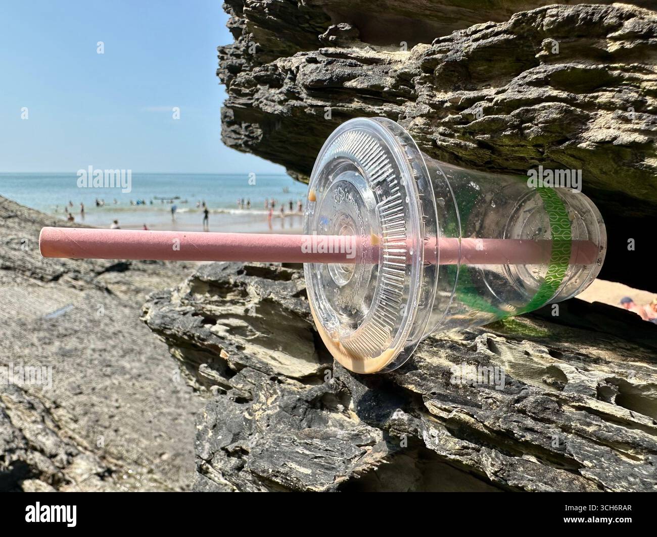 Una tazza di plastica incastrata in una roccia a Mwnt Bay, nel Galles del Sud - Immagine stock catturata con smartphone
