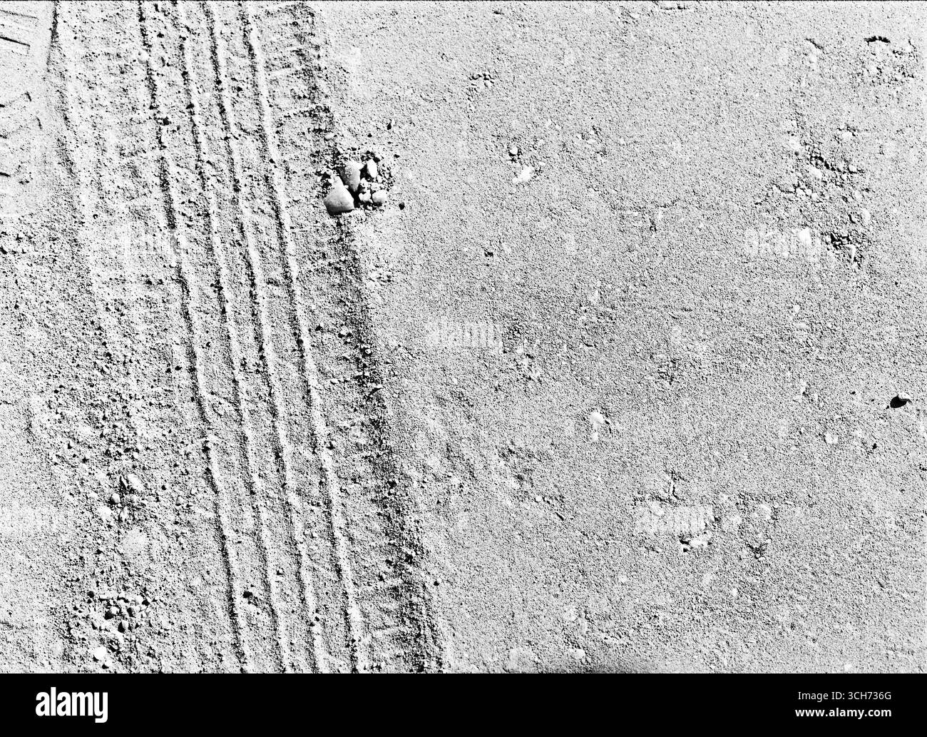 Fotografia in bianco e nero di una pista di uno pneumatico impressa sulla sabbia. Foto Stock