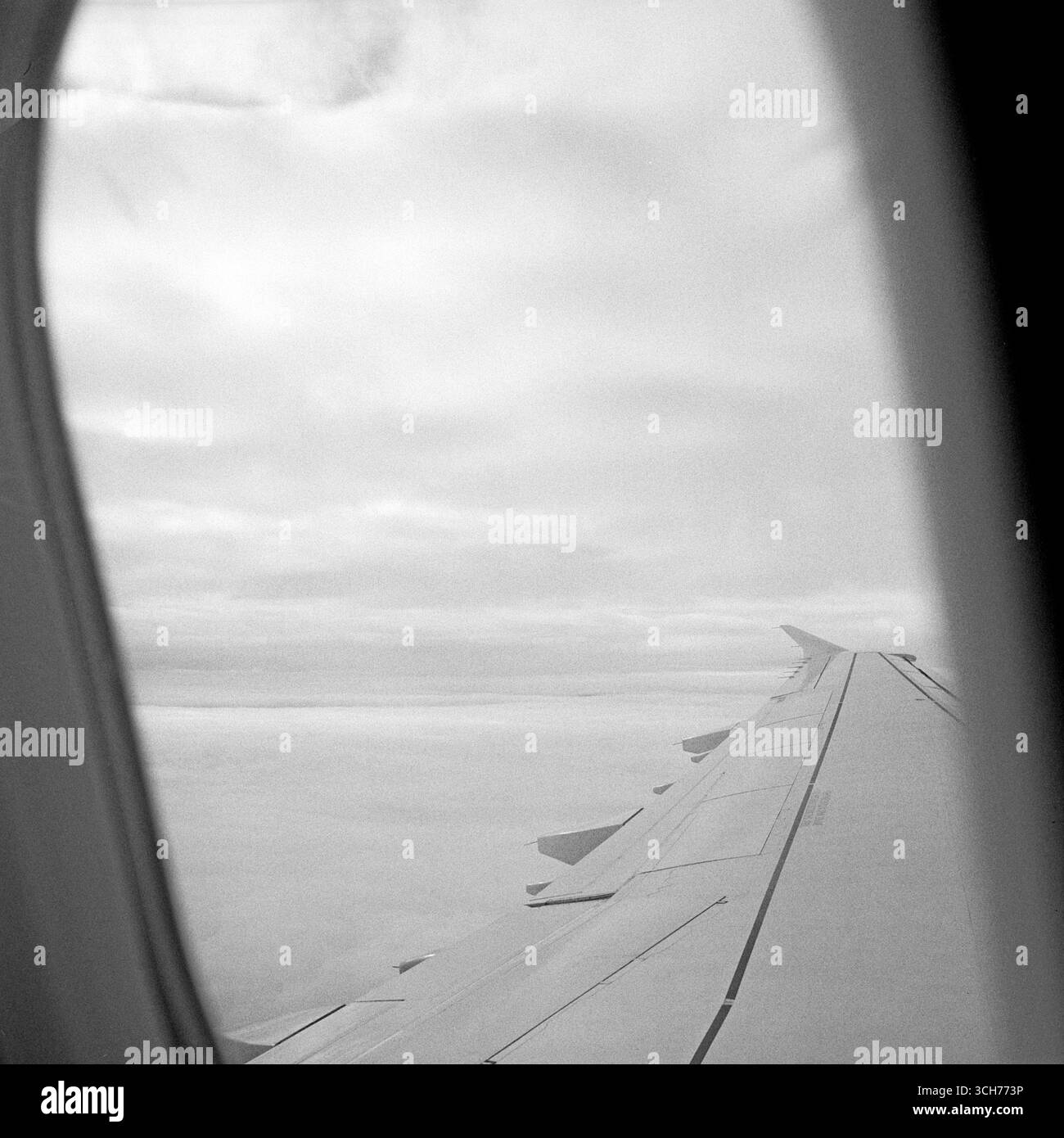 Ala dell'aereo sopra le nuvole: Formato quadrato bianco e nero dal posto vicino al finestrino Foto Stock