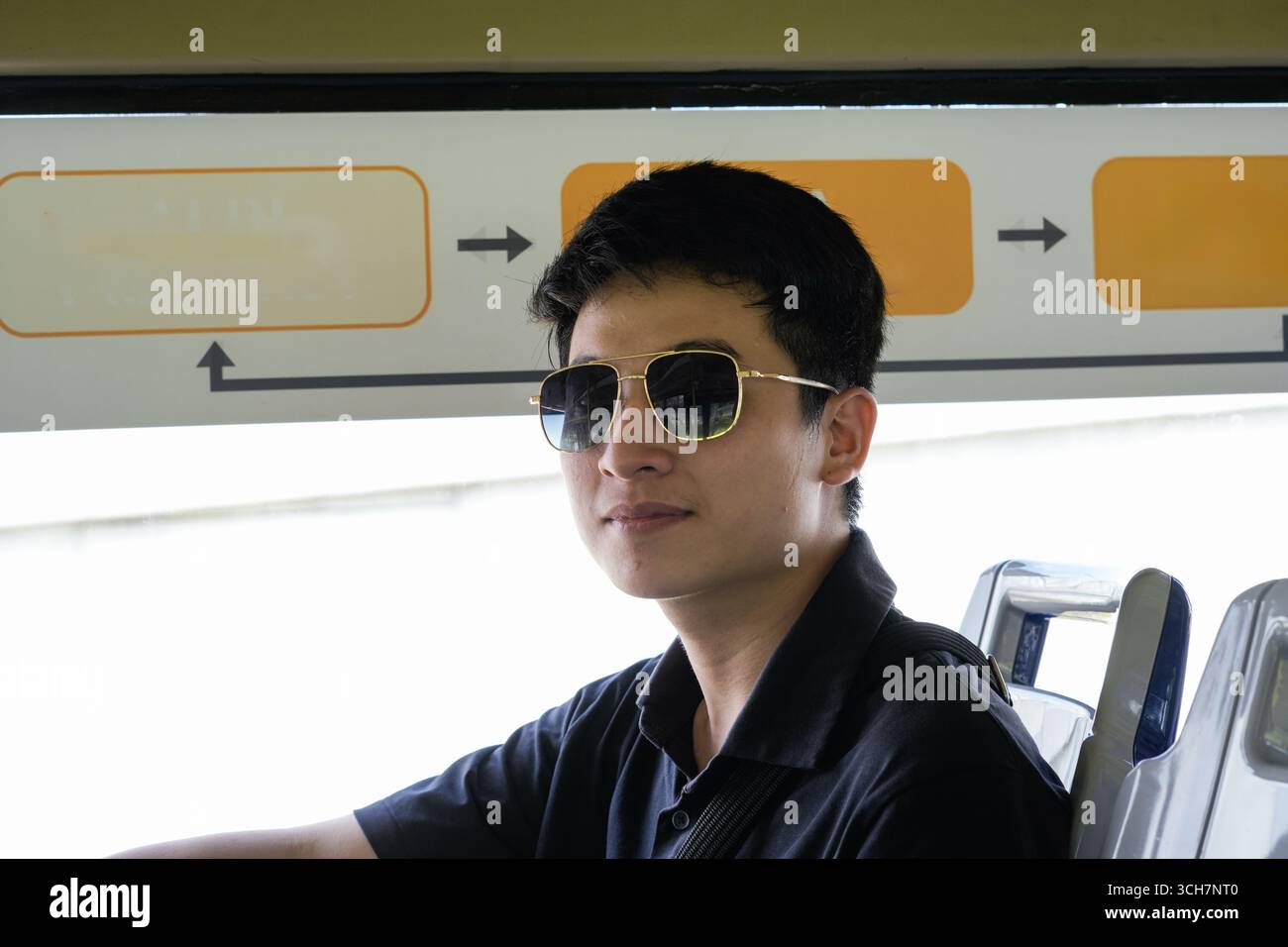 Giovane uomo con occhiali da sole, autobus che guarda fuori dal finestrino, atmosfera e stile di viaggio rilassati Foto Stock