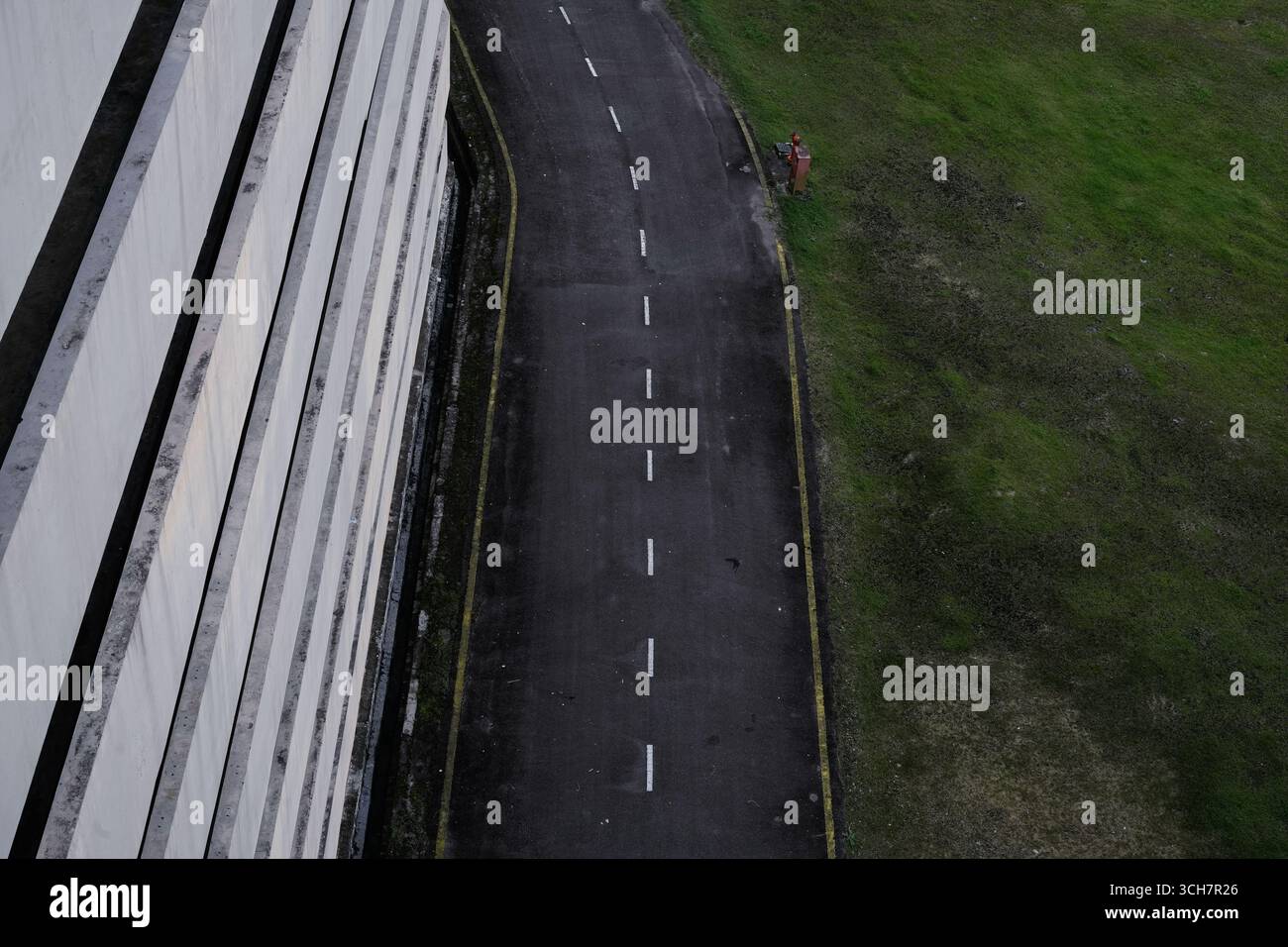veduta aerea della stretta strada curva che corre lungo alte pareti bianche e campo verde Foto Stock