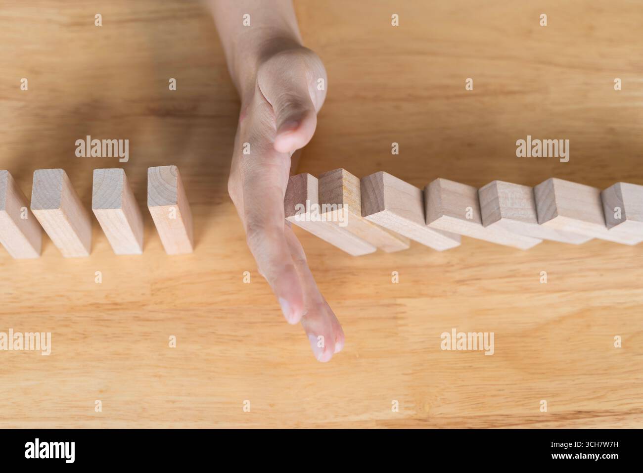 Concetto di prevenzione dei rischi e gestione delle crisi che mostra l'arresto manuale della catena di domino in caduta per evitare ulteriori perdite, rappresentando la decisione aziendale ma Foto Stock