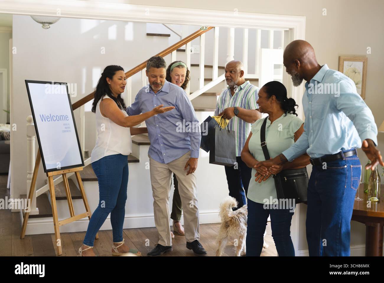 Accogliendo gli amici a casa, gruppi diversi che si divertono a radunarsi con il cane. Amicizia, celebrazione, diversità, animali domestici, ospitalità, felicità Foto Stock