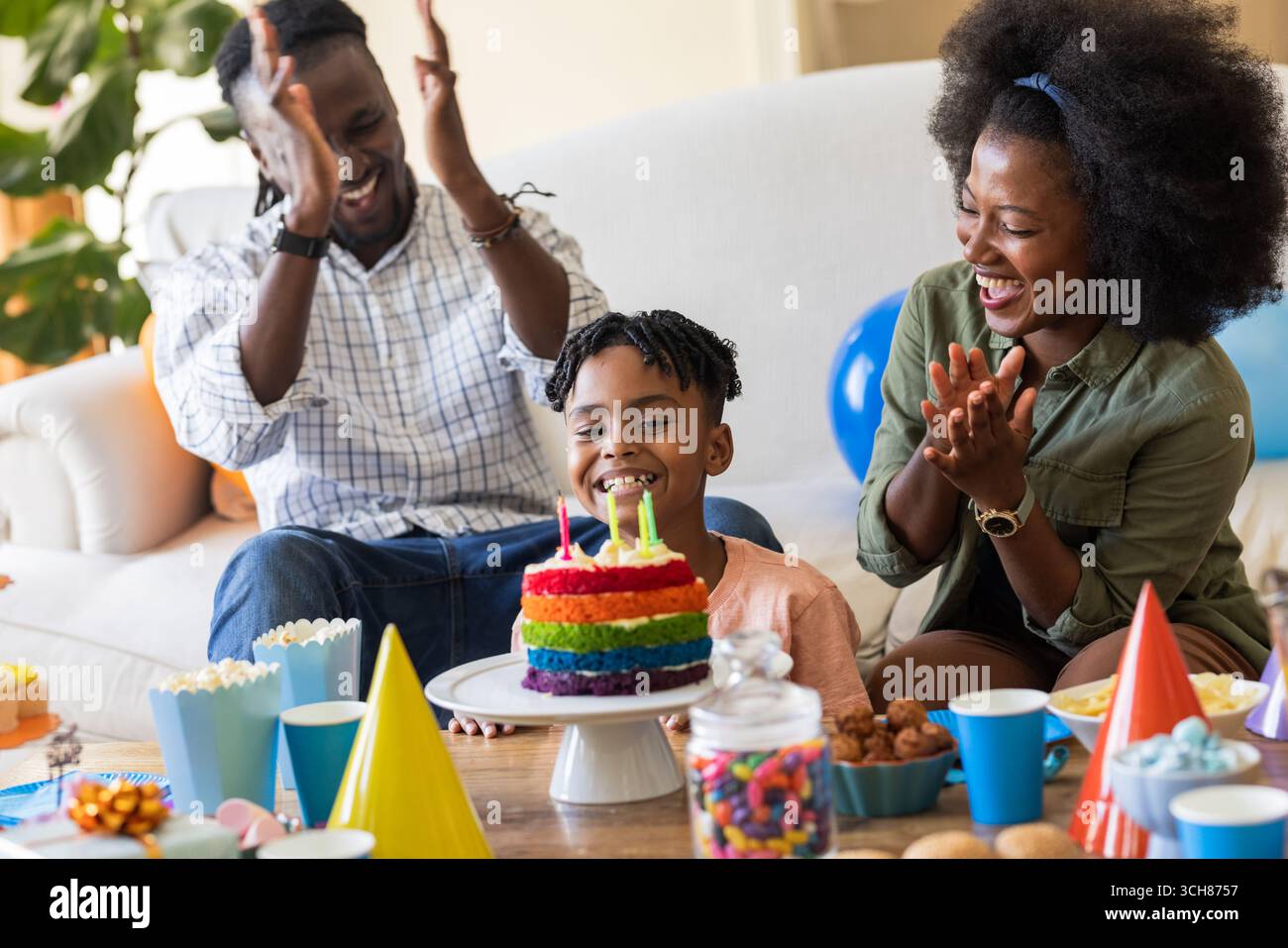 La famiglia festeggia il compleanno del bambino con torte colorate e decorazioni a casa Foto Stock