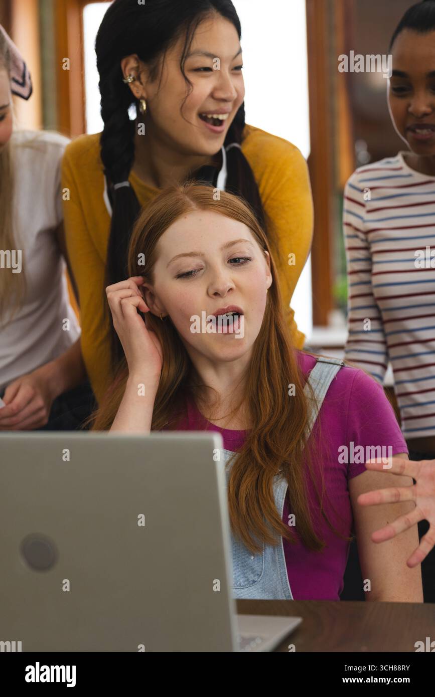 Ragazzi che festeggiano notizie entusiasmanti mentre sono riuniti intorno al notebook a casa Foto Stock