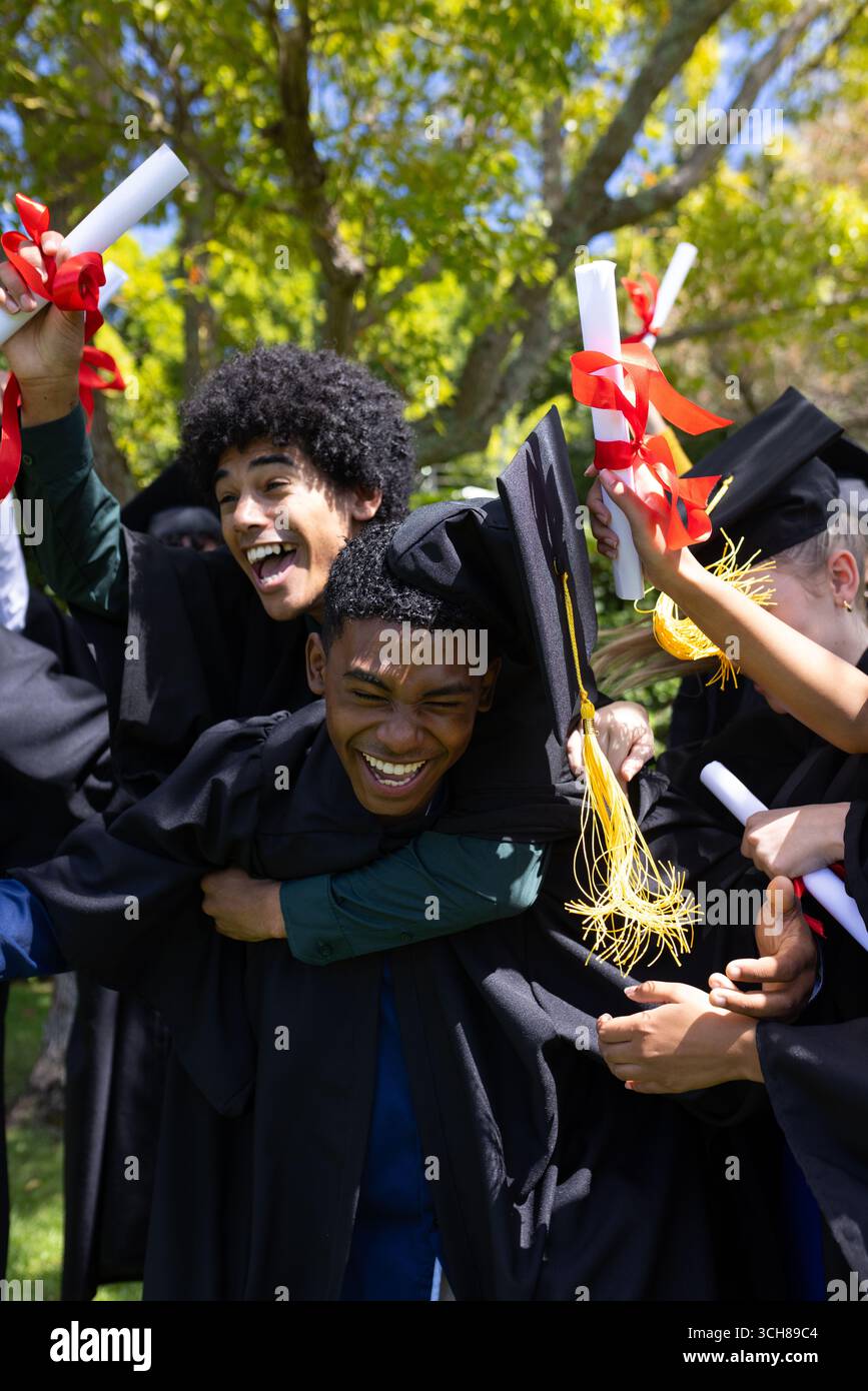 Laureati in berretti e abiti per celebrare l'aperto, in possesso di diplomi Foto Stock