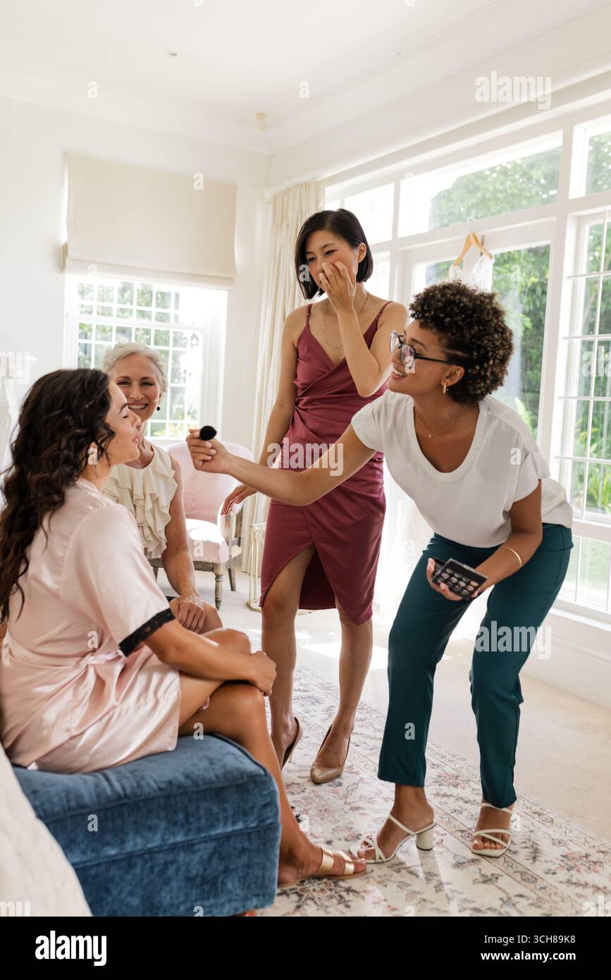 Le damigelle d'onore ridono e fanno il trucco mentre si preparano per la celebrazione del matrimonio Foto Stock Le damigelle d'onore ridono e fanno il trucco mentre si preparano per la celebrazione del matrimonio Foto Stock