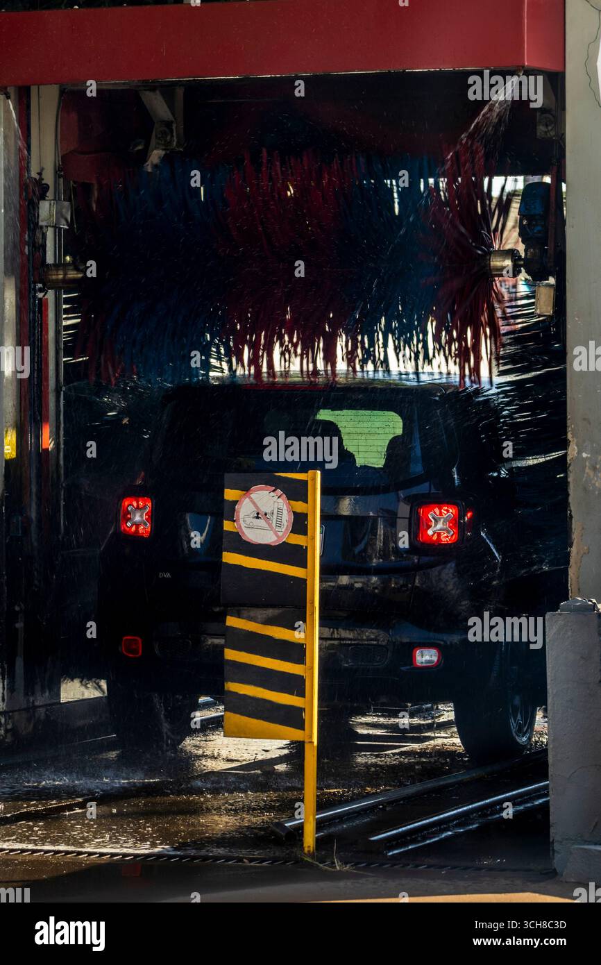 Marilia, SP, Brasile, 21 agosto 2025. Un'auto nera passa attraverso un autolavaggio automatico in una stazione di servizio a Marília, SP. Getti d'acqua e spazzole rotanti Foto Stock
