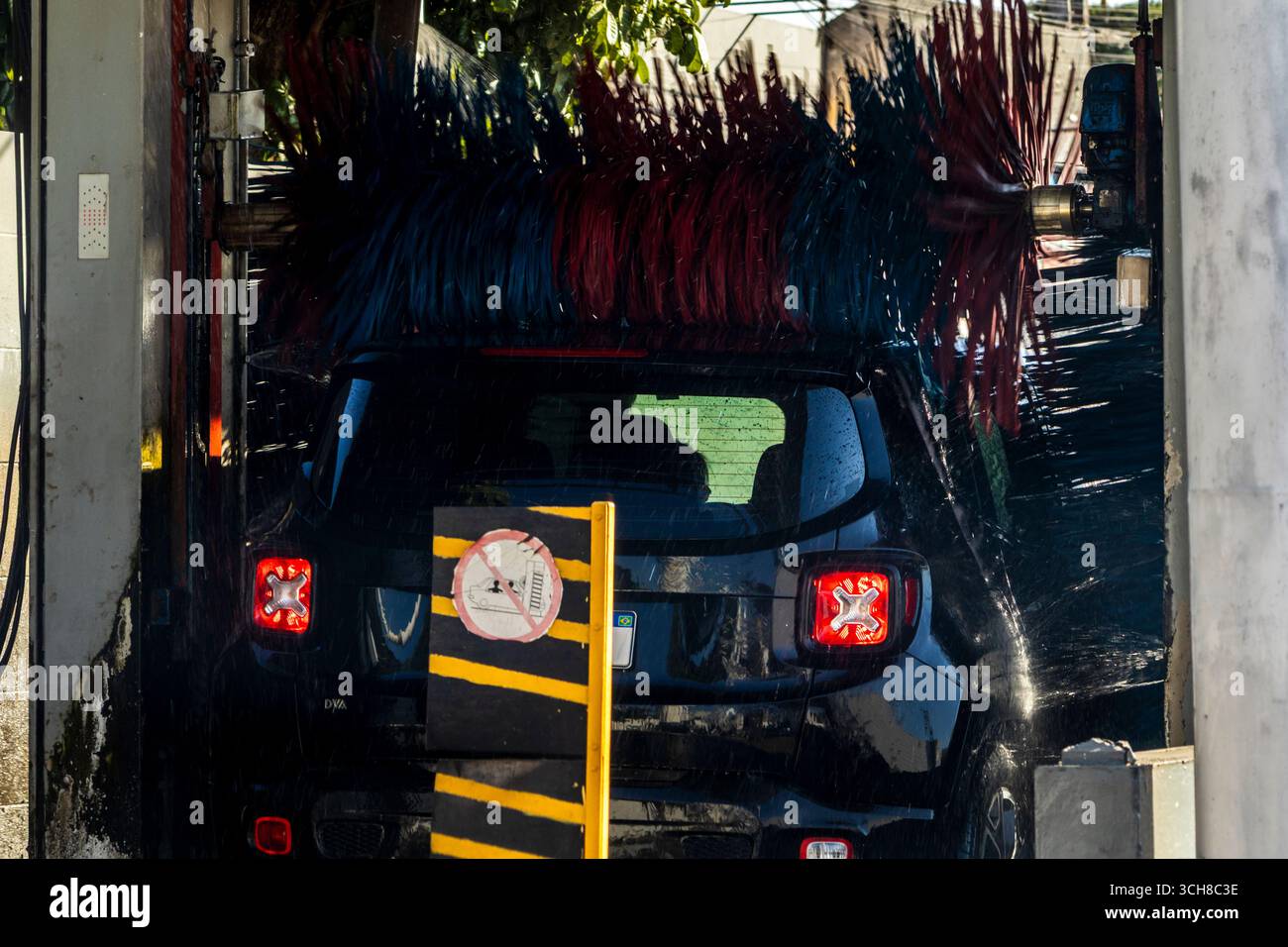 Marilia, SP, Brasile, 21 agosto 2025. Un'auto nera passa attraverso un autolavaggio automatico in una stazione di servizio a Marília, SP. Getti d'acqua e spazzole rotanti Foto Stock