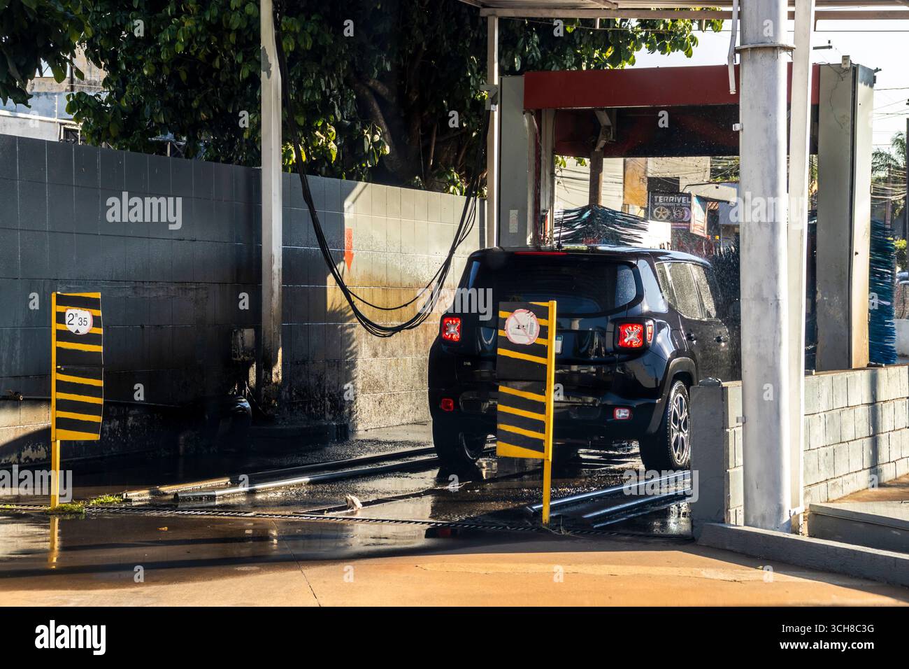 Marilia, SP, Brasile, 21 agosto 2025. Un'auto nera passa attraverso un autolavaggio automatico in una stazione di servizio a Marília, SP. Getti d'acqua e spazzole rotanti Foto Stock
