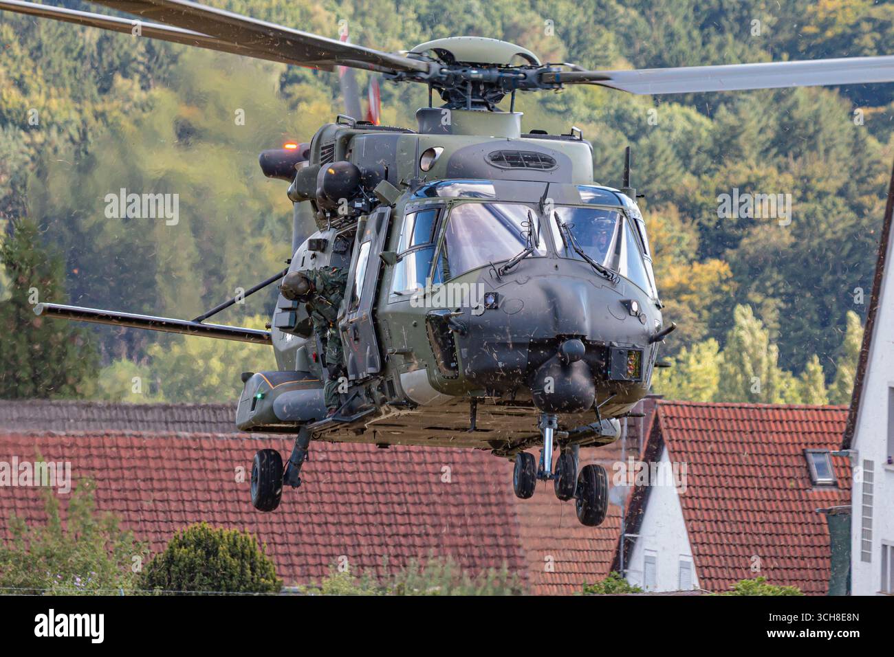 Un elicottero militare tedesco della Bundeswehr NH90 vola basso durante un'esercitazione NATO, gettando polvere mentre esegue manovre tattiche. La scena mostra dyna Foto Stock