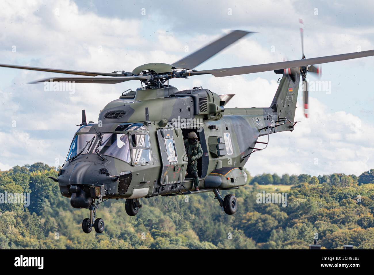 Un elicottero militare tedesco della Bundeswehr NH90 vola basso durante un'esercitazione NATO, gettando polvere mentre esegue manovre tattiche. La scena mostra dyna Foto Stock