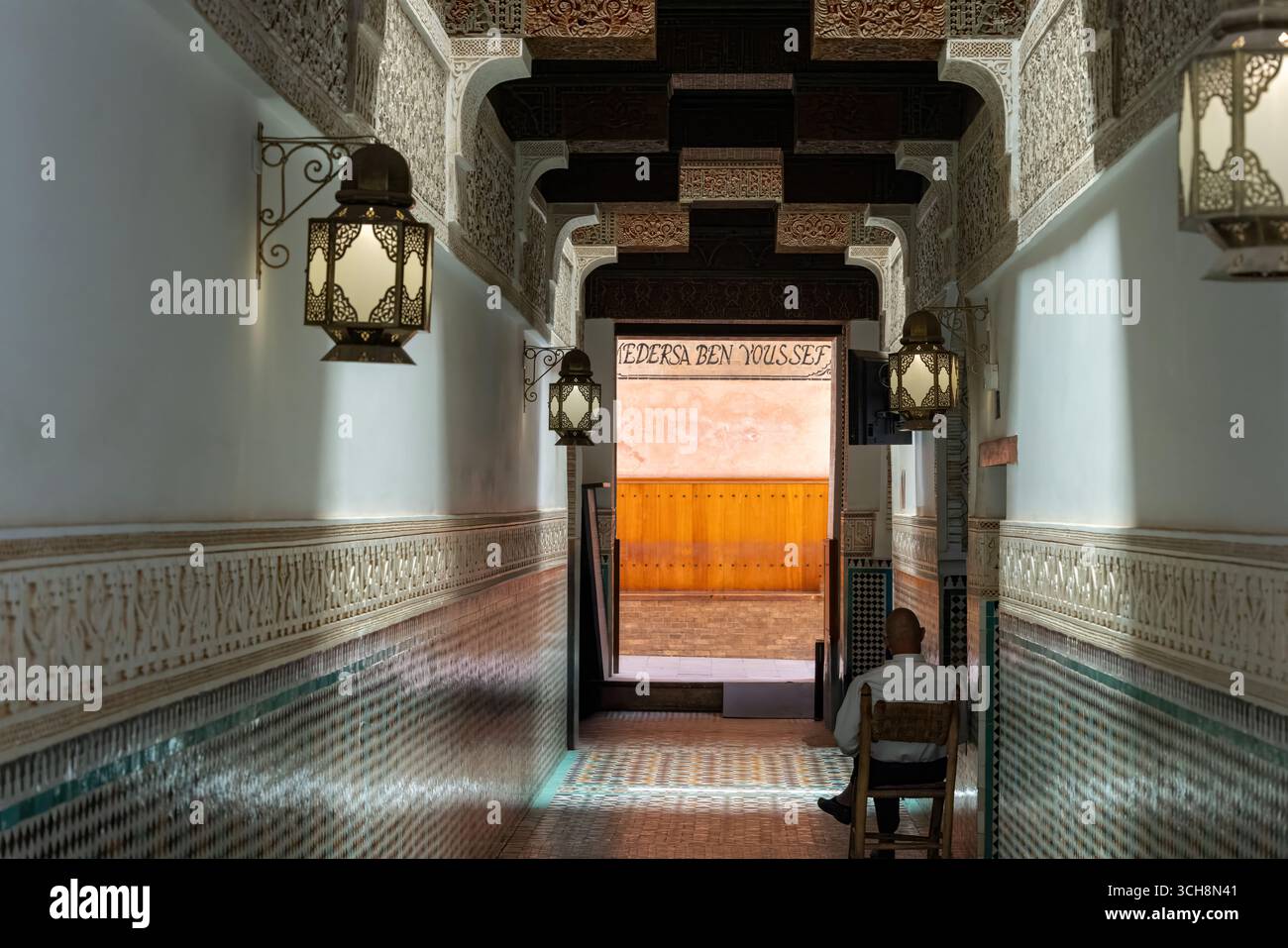 Corridoio d'ingresso della Madrasa Ben Youssef (Medersa Ben Youssef), Marrakech, Marocco, con piastrelle zellige, stucchi scolpiti e lanterne sospese. Foto Stock