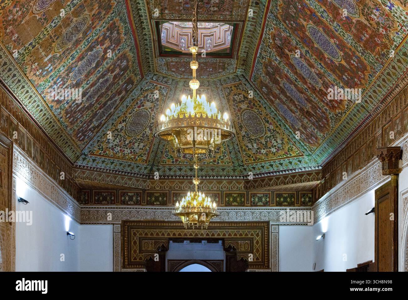 Sala ricevimento decorata con soffitto in legno di cedro dipinto, lampadario e caminetto piastrellato all'interno del Palazzo Bahia (Palais Bahia), Marrakech, Marocco. Foto Stock