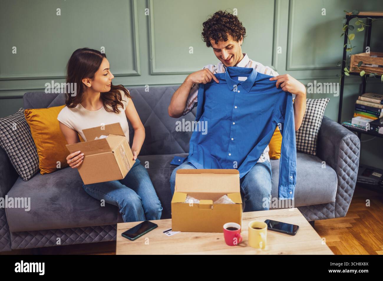 Una coppia ama disimballare un pacchetto insieme, ritrarre lo shopping quotidiano a casa e la gioia di ricevere ordini online. Foto Stock