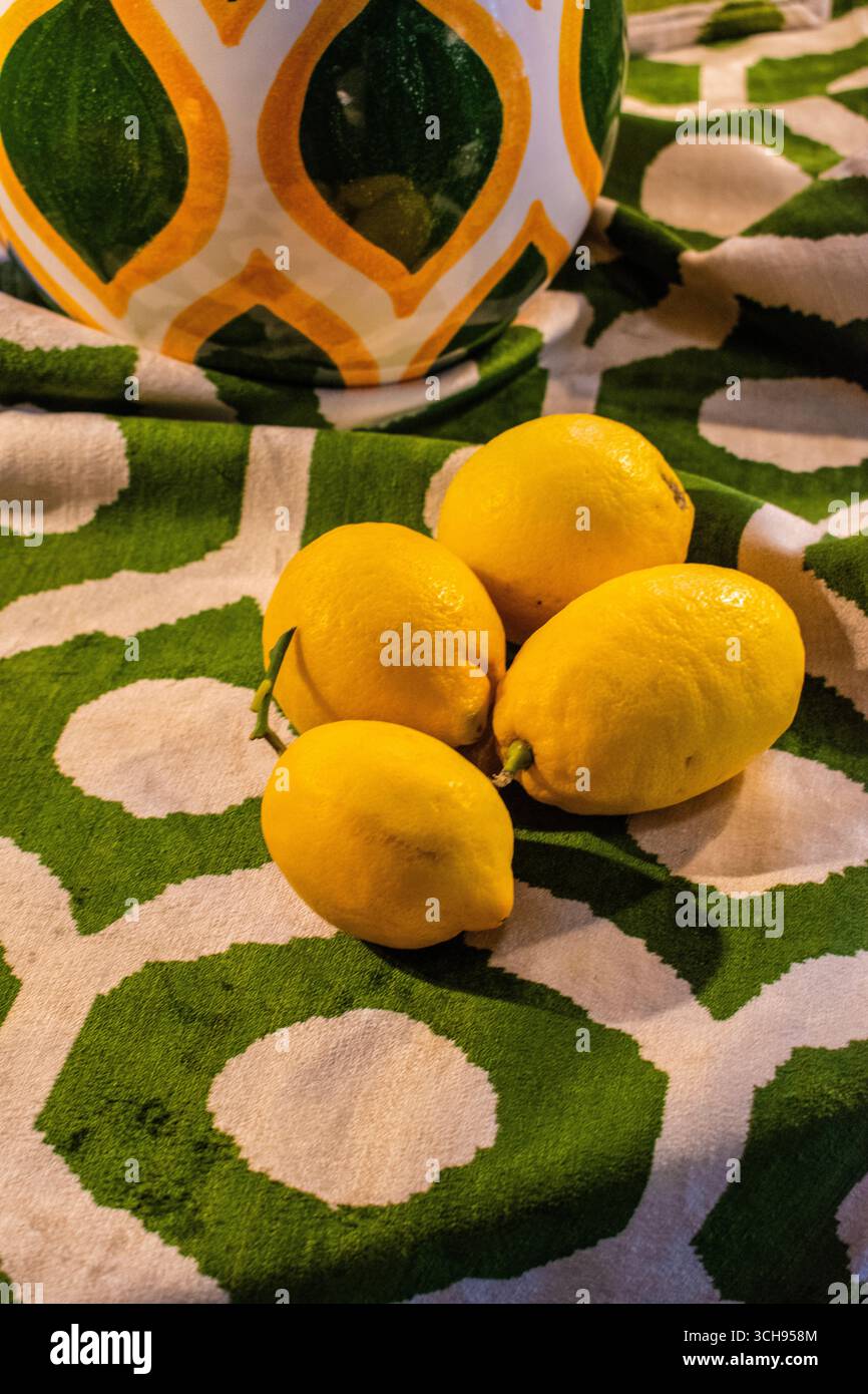 Milano, Italia, Europa: Natura morta, dettagli di quattro limoni gialli a su una tovaglia bianca con disegni verdi Foto Stock