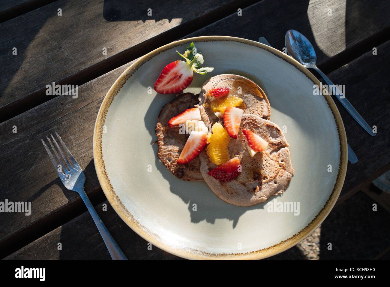 Pancake di grano saraceno con fette di frutta su un piatto su un tavolo di legno Foto Stock