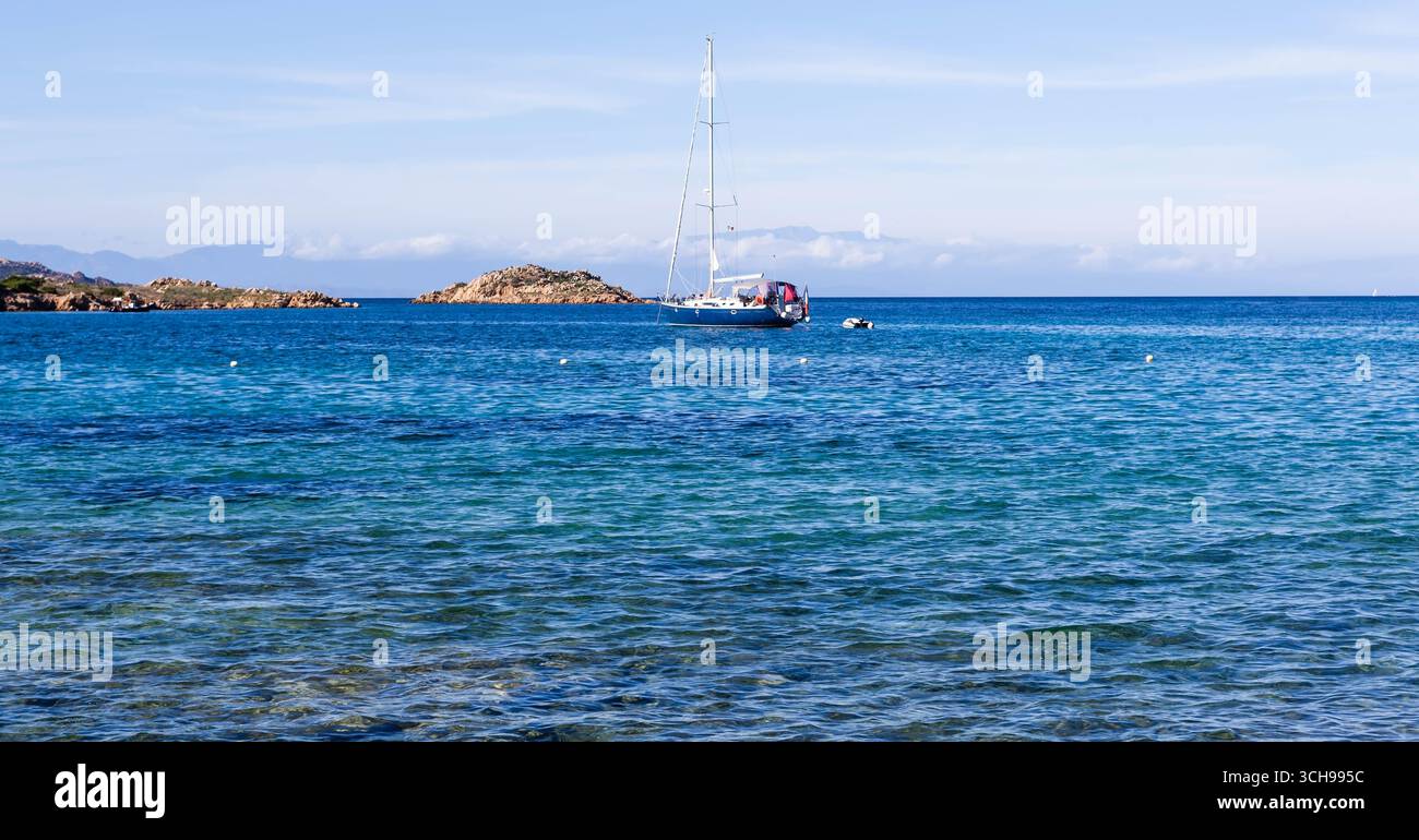 Una barca a vela riposa nelle acque turchesi di Cala Garibaldi, Caprera, Italia. Foto Stock