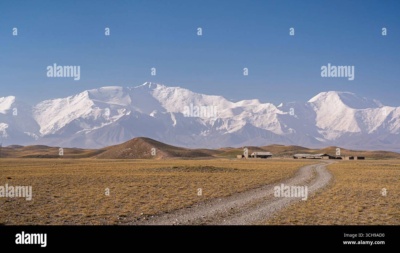 Vista panoramica del paesaggio di fine estate del Lenin Peak innevato e del Dzerzhinsky Peak nella catena montuosa del Trans Alay, Sary Mogol, Kirghizistan Foto Stock