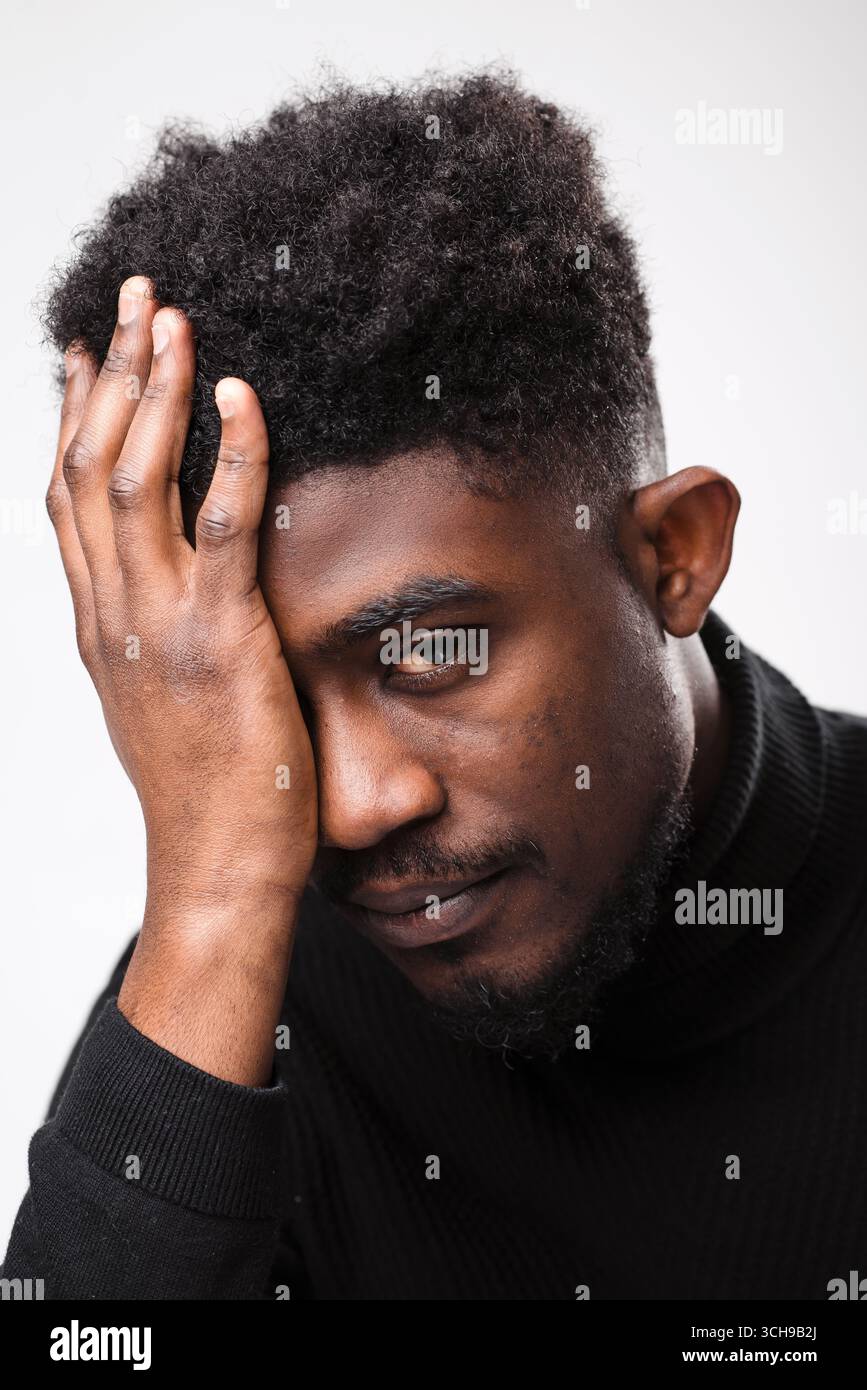 Faccia da vicino di un giovane uomo nero triste Foto Stock