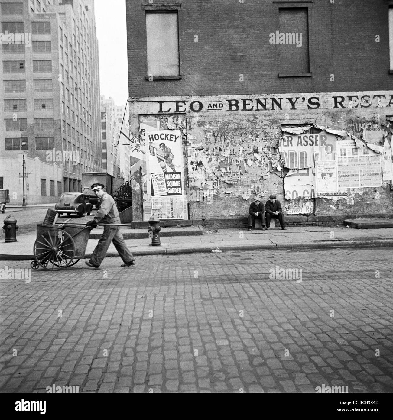 New York, New York. Un pulitore di strada su Washington Street - poster di Hockey per la partita dei New York Rangers al Madison Square Garden - foto di John Vachon 1943 Foto Stock