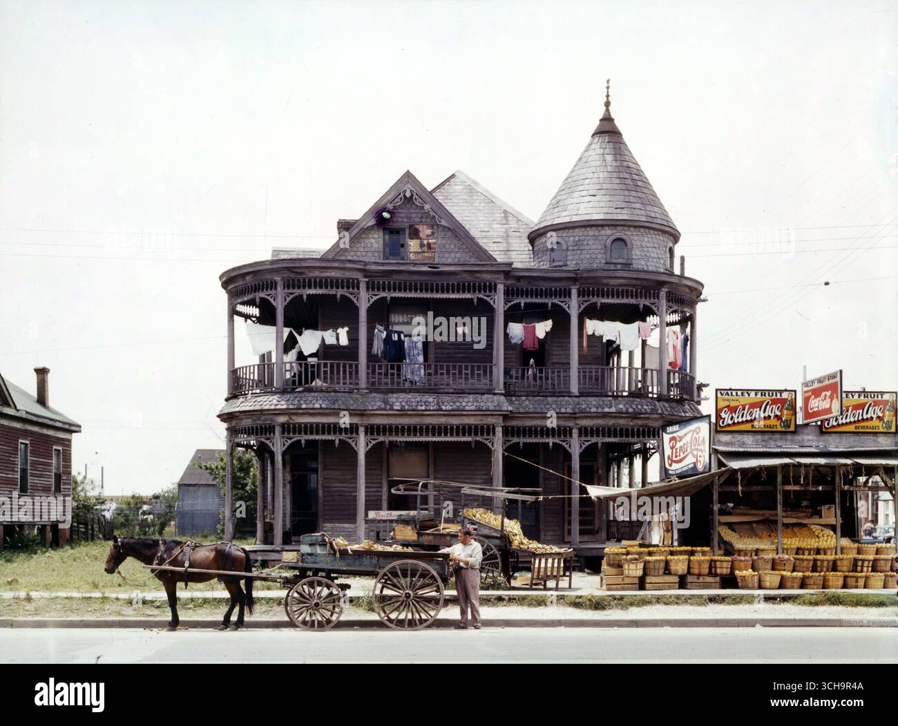 Casa a Houston, Texas, maggio 1943. Fotografia a colori FSA di John Vachon. Mostra la casa in legno in stile vittoriano, la lavanderia appesa alla galleria superiore; di fronte c'è un carro trainato da cavalli. A destra della foto c'è uno stand di frutta e dei cartelli pubblicitari Foto Stock